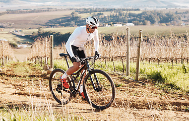 Image showing Man, bike and cycling on gravel in nature, countryside and training of triathlon, sports and power. Cyclist, bicycle and off road adventure on hill for travel, fitness or professional cardio exercise