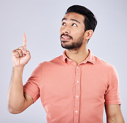 Image showing Mockup, Asian man and pointing for space, advertising and happiness against grey studio background. Japan, male and guy with gesture for product placement, branding or gen z with confidence and relax