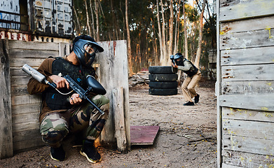 Image showing Sports, paintball and man with gun for battle, game or competition outdoors on field. War, military camouflage and male soldier with weapon on shooting range to hide from player in exercise fight.