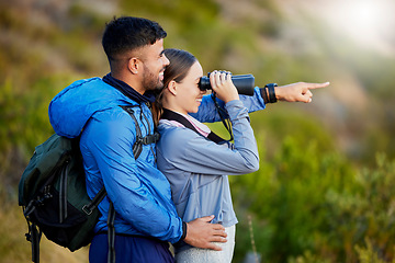 Image showing Binoculars, point and a couple bird watching in nature while hiking in the mountains together. Forest, ecology or sightseeing with a man and woman looking at the view while bonding on a hike