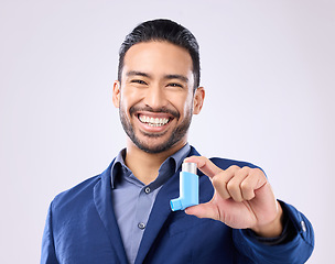 Image showing Asthma, pump and portrait with a man in studio on a gray background holding a respiratory device for breathing. Happy, smile and a handsome young male with an inhaler to relieve coughing or wheezing