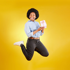 Image showing Jump, excited and black woman with gift in air on yellow background with energy, happy and smile in studio. Birthday mockup, celebrate and isolated girl jumping with present, box and surprise package