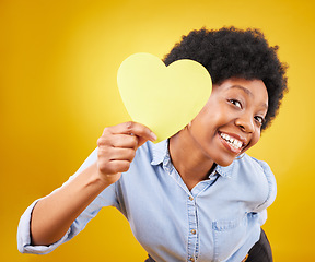 Image showing Portrait, heart and social media with a black woman in studio on a yellow background for love or affection. Emoji, shape and romance with an attractive young female feeling excited for valentines day