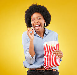 Image showing Happy, smile and popcorn with black woman in studio for movie, streaming service and cinema. Laugh, comedy and theatre with female and snack isolated on yellow background for food, tv and film