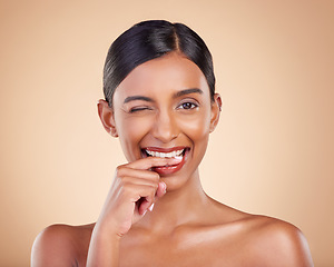 Image showing Flirty, beauty and portrait of a winking woman isolated on a studio background. Happy, sexy and face of an Indian model with makeup, cosmetics and attitude on a backdrop to advertise lipstick