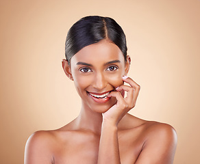 Image showing Portrait, beauty and biting finger with a model woman in studio on a beige background for skincare. Face, mouth and flirt with an attractive young female posing for cosmetics or luxury wellness