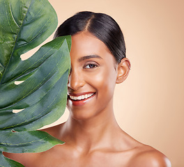 Image showing Portrait, skincare and palm leaf with a model woman in studio on a beige background for natural beauty. Face, plants and nature with an attractive young female posing for cosmetics or luxury wellness