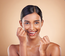 Image showing Portrait, dental floss and cleaning with a model woman in studio on a beige background to promote oral hygiene. Face, mouth and teeth with an attractive young female posing for a dentist product