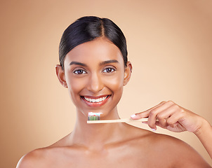 Image showing Portrait, toothbrush and toothpaste with a model woman in studio on a beige background for dental or oral hygiene. Face, mouth and dentist with an attractive young female cleaning or brushing teeth