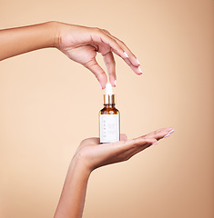 Image showing Hands, product and antiaging serum with a woman in studio on a beige background to promote skincare. Marketing, advertising and luxury with a female holding a bottle for the promotion of beauty