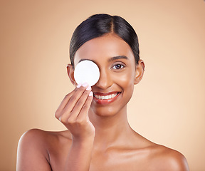 Image showing Portrait, skincare and cotton swab with a model woman in studio on beige background to promote beauty. Face, eye and exfoliate with an attractive young female posing for cosmetics or luxury wellness