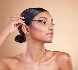 Image showing Makeup, product and woman with mascara for eyelashes isolated on a studio background. Thinking, cosmetology and Indian girl with a brush for applying cosmetics, pomade or treatment to lashes