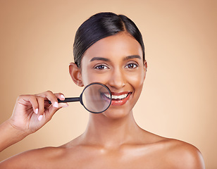 Image showing Portrait, skincare and magnifying glass with a model woman in studio on a beige background searching for beauty. Face, investigation and smile with an attractive female looking for luxury cosmetics