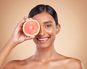 Image showing Portrait, beauty and grapefruit with a model woman in studio on a beige background to promote skincare. Face, eye and fruit with an attractive young female posing for natural or organic cosmetics