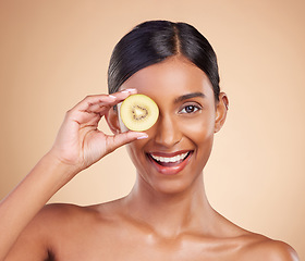 Image showing Portrait, beauty and kiwi with a model woman in studio on a beige background to promote skincare. Face, eye and fruit with an attractive young female posing for organic, natural or luxury cosmetics