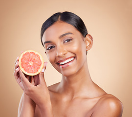 Image showing Portrait, skincare and grapefruit with a model woman in studio on a beige background to promote beauty. Face, fruit and natural with an attractive young female posing for organic or luxury cosmetics