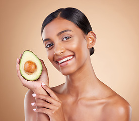 Image showing Portrait, beauty and avocado with a woman in studio on a beige background to promote skincare. Face, fruit and antioxidants with an attractive young female posing for organic or natural cosmetics