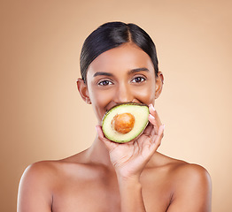 Image showing Portrait, skin or avocado with a model woman in studio on a beige background to promote beauty. Face, eyes and fruit with an attractive young female posing for organic, natural or luxury antioxidants