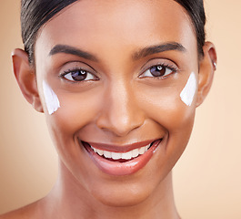 Image showing Portrait, face and cream with a model woman in studio on a beige background closeup for skincare. Beauty, facial and lotion with an attractive young female smiling for antiaging cosmetic treatment