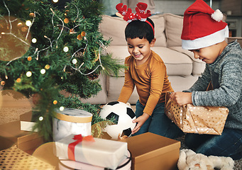 Image showing Festive, happy and children with christmas gifts opening boxes by the tree for celebration. Happiness, holiday and kid siblings with presents in the living room to celebrate xmas at their family home