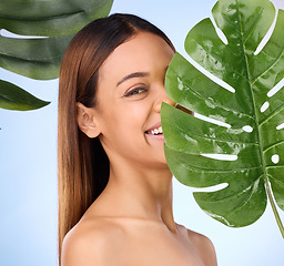 Image showing Woman, portrait and leaf in natural beauty skincare cosmetics or self love and care against blue studio background. Happy female smile for perfect skin, leafy green organic plant or sustainable eco