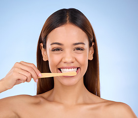 Image showing Portrait, toothbrush and smile with a model woman in studio on a blue background for oral hygiene. Mouth, cleaning and dental with an attractive young female brushing her teeth for whitening