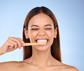 Image showing Toothbrush, toothpaste and cleaning with a woman in studio on a blue background for oral hygiene. Mouth, dentist and dental with an attractive young female brushing her teeth for healthy gums