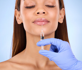 Image showing Face, lips and injection of woman on studio, blue background and facial cosmetics. Young female model, lip filler and needle for plastic surgery, skincare transformation and aesthetic mouth change