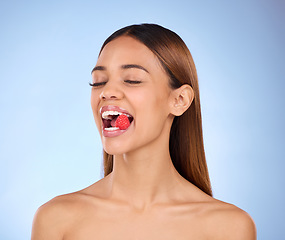 Image showing Beauty, woman and face with raspberry for skincare dermatology cosmetics in studio. Female model person on a blue background for self care, facial glow and healthy or clean skin with natural fruit