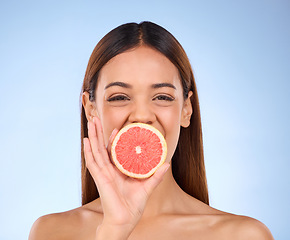 Image showing Grapefruit, woman and beauty face portrait for skincare dermatology and vitamin c. Female model on a blue background for self care, facial glow and healthy fruit for natural and clean skin in studio