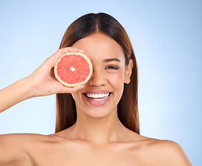 Image showing Beauty, grapefruit and woman for face portrait with a smile for skincare dermatology and vitamin c. Model on blue background for self care, facial glow and healthy fruit for natural skin in studio