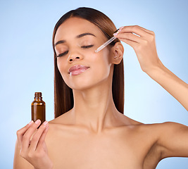 Image showing Beauty, skincare and cosmetics, hispanic woman with serum in pipette for anti aging skin glow on blue background. Makeup, facial repair and face of model with solution or collagen product in studio.