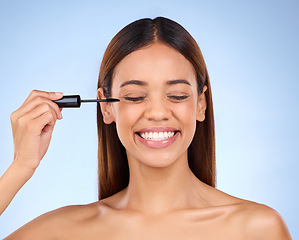 Image showing Woman, beauty and mascara makeup for eyes with cosmetics on face in studio. Female model person smile on a blue background for self care, facial glow and eyelash extension or luxury growth product