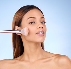 Image showing Beauty, makeup brush and blush with woman in studio for cosmetics, tools and self care. Glow, foundation and face with girl model on blue background for facial, powder and cosmetology product