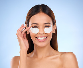 Image showing Skincare, beauty and portrait of happy woman with eye mask for anti aging or skin glow on blue background. Cosmetics, facial repair pads and face of model with collagen product and smile in studio.