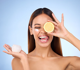 Image showing Woman, moisturizer cream and lemon for natural skincare, beauty and vitamin C against a blue studio background. Female holding citrus fruit, creme or lotion for healthy organic nutrition or facial