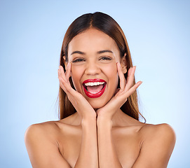 Image showing Makeup, hands on face and red lipstick portrait with beauty cosmetics in studio. Excited aesthetic female model on blue background for self care, facial glow and shine or color for skin and wellness