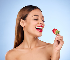 Image showing Beauty, health and strawberry with woman in studio for nutrition, diet and detox. Organic food, natural cosmetics and self care with girl model eating fruit on blue background for wellness and glow