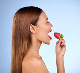 Image showing Beauty, wellness and profile of woman with strawberry on blue background for diet, nutrition and healthy eating. Skincare, happy and girl with fruit in studio for cosmetics, makeup and natural snack