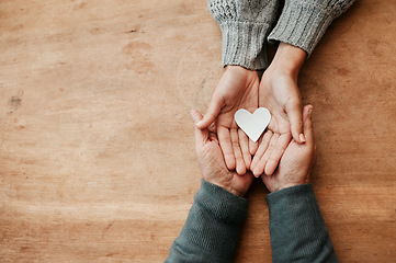 Image showing Hands, heart and shape for love, support or care above in trust, unity or compassion together on mockup table. Top view of hand holding for family generation, hope or symbol in bonding relationship