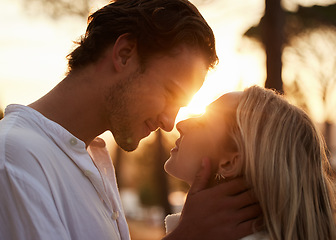 Image showing Couple, love and kiss outdoor at sunset for love, care and romance with hands on face on a date. Young man and woman together on valentines day with lens flare, peace and freedom in nature forest