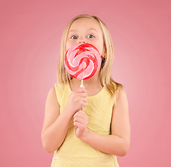 Image showing Candy, sugar rush and lollipop with girl in studio for sweets, party and carnival food isolated on pink background. Cute, excited and youth with child and eating colorful snack for playful and treat