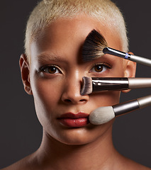 Image showing Woman, portrait and makeup brushes on face for beauty cosmetics, skincare or treatment against a gray studio background. Beautiful female holding cosmetic brushing tools for facial, self care or love