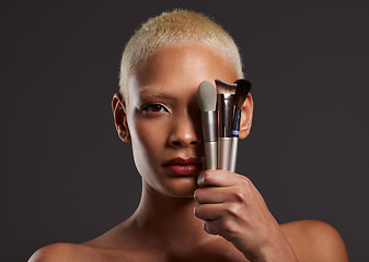 Image showing Woman, portrait and makeup brushes for facial beauty cosmetics, skincare or treatment against a gray studio background. Beautiful female holding cosmetic brushing tools on face for self care or love