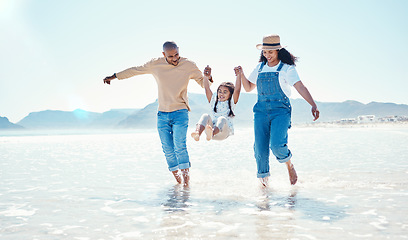 Image showing Playing, parents and girl in water at beach for bonding, quality time and summer adventure together. Travel, family and happy mom and dad swinging child enjoy holiday, vacation and relax on weekend