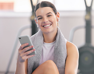 Image showing Gym, smile and relax, woman with phone and earphones on workout break reading messages or social media. Exercise, rest and person with smartphone for fitness app, music or networking for motivation.