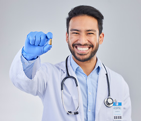 Image showing Happy, portrait and doctor with pill in studio, smile for medicine, vitamin or cure on grey background. Medical, innovation and face of male healthcare expert with futuristic health supplement