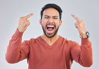 Image showing Angry, middle finger and portrait of asian man in studio for rude, conflict and problem. Annoyed, upset and aggressive with male and hand gesture on gray background for hate, disrespect and furious