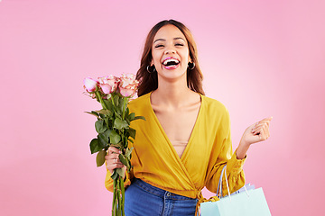 Image showing Happy, shopping bags and flowers with woman in studio for retail, birthday and spring. Event, party and celebration with female customer and roses on pink background for sale, discount and romance