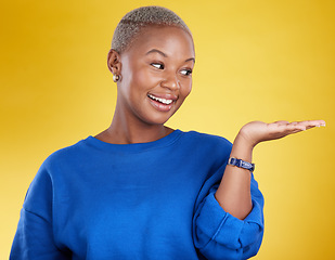 Image showing Mock up, smile and black woman with product placement in studio isolated on a yellow background. Mockup promotion, happy and African female with palm for advertising, marketing and branding space.